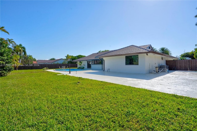 back of house featuring a fenced in pool, a patio area, a lawn, and central AC unit