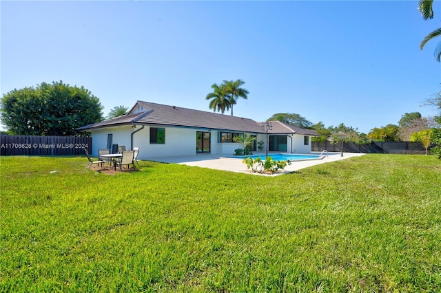 back of property with a patio area, a fenced in pool, and a yard