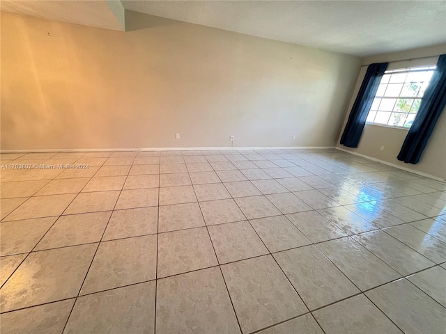 tiled empty room featuring a textured ceiling