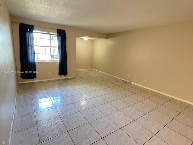 unfurnished room featuring light tile patterned floors and a textured ceiling