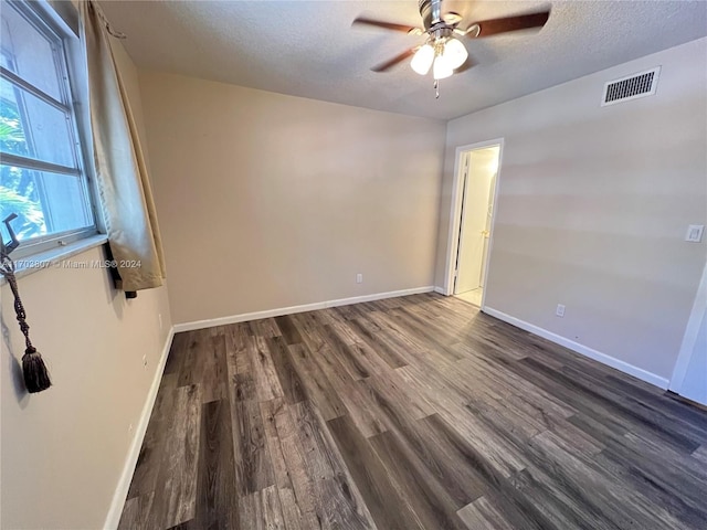 unfurnished room featuring ceiling fan, dark wood-type flooring, and a textured ceiling