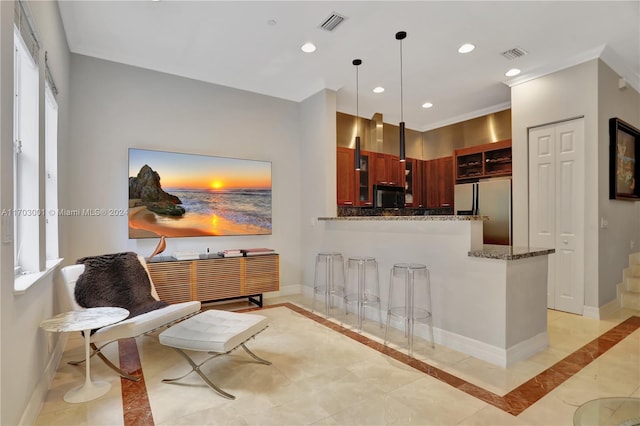 kitchen featuring stainless steel fridge, decorative light fixtures, a wealth of natural light, and dark stone countertops