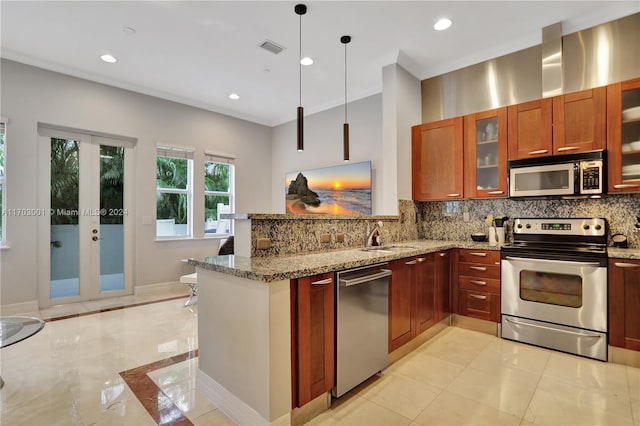 kitchen featuring light stone countertops, sink, stainless steel appliances, kitchen peninsula, and decorative light fixtures