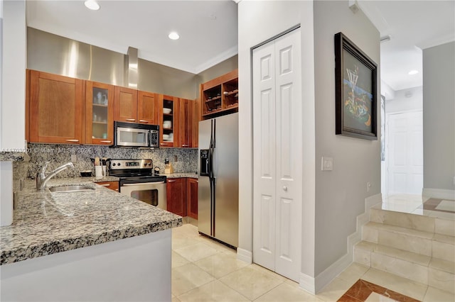 kitchen featuring light stone countertops, appliances with stainless steel finishes, decorative backsplash, sink, and light tile patterned floors