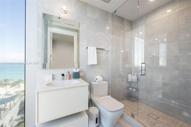 bathroom with a shower with door, vanity, tile walls, and toilet