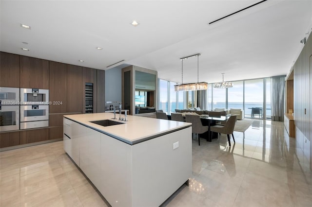 kitchen featuring a wealth of natural light, floor to ceiling windows, sink, a water view, and a center island with sink