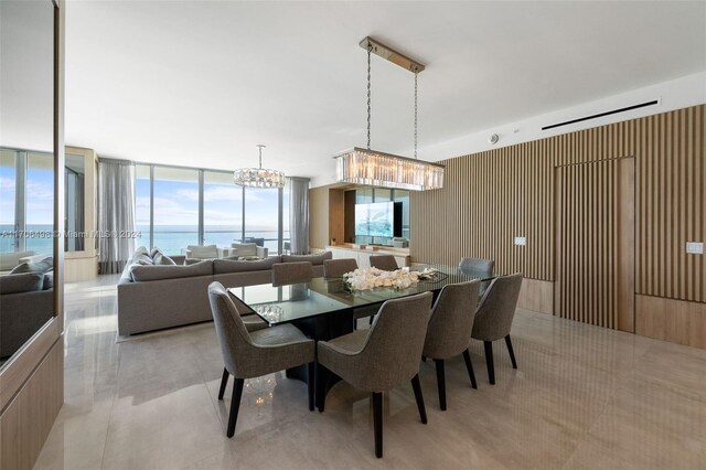 dining area with expansive windows, a water view, and a chandelier