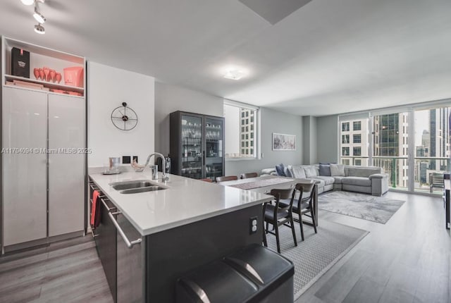 kitchen with sink, a wall of windows, kitchen peninsula, and light wood-type flooring