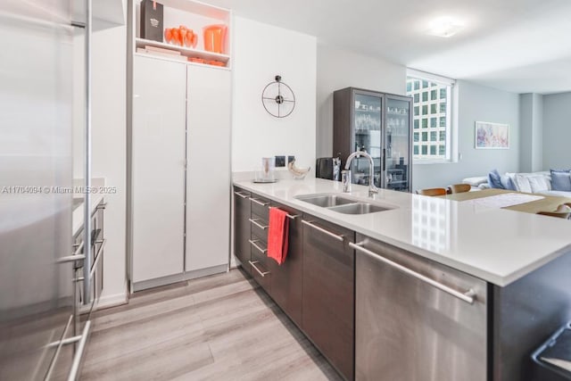 kitchen with light hardwood / wood-style floors, sink, kitchen peninsula, and stainless steel appliances