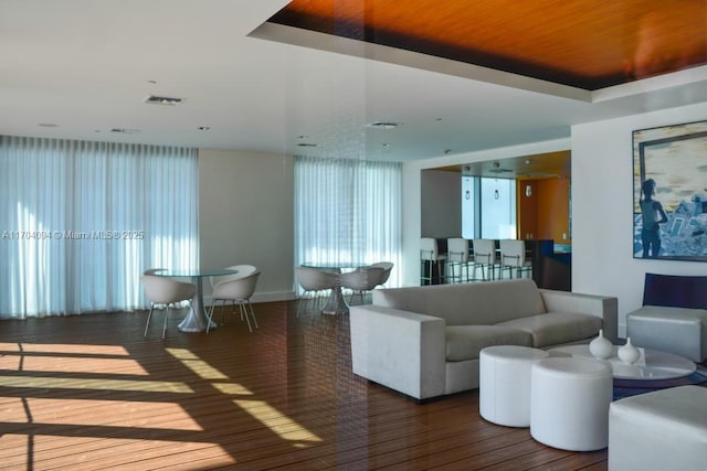 living room with a raised ceiling and hardwood / wood-style flooring