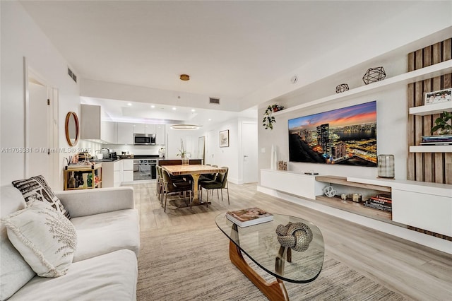 living area with recessed lighting, visible vents, and light wood-type flooring