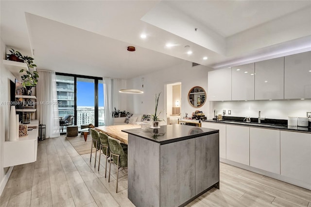 kitchen with recessed lighting, light wood-style floors, a kitchen island, dark countertops, and modern cabinets