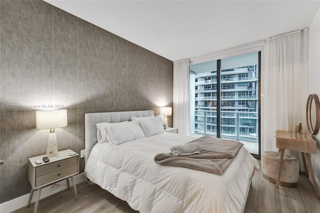 bedroom with floor to ceiling windows and hardwood / wood-style floors