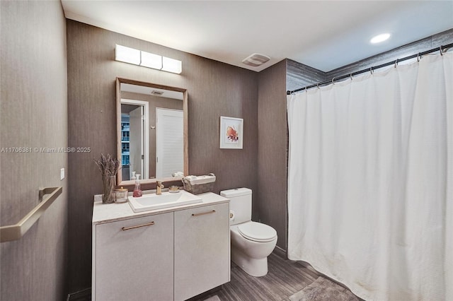 bathroom with a shower with shower curtain, toilet, wood finished floors, and vanity