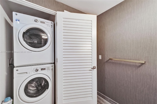 laundry room featuring wood-type flooring and stacked washer / drying machine