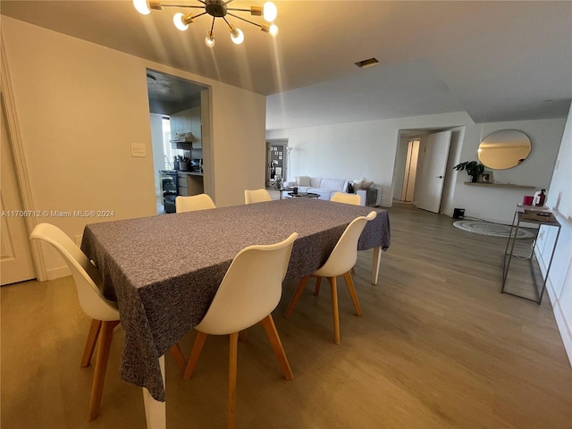 dining room featuring wood-type flooring and an inviting chandelier