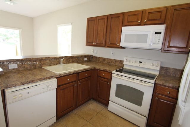 kitchen with kitchen peninsula, white appliances, sink, and light tile patterned floors