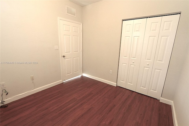 unfurnished bedroom featuring a closet and dark hardwood / wood-style flooring