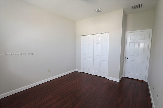 unfurnished bedroom with dark hardwood / wood-style floors and a closet