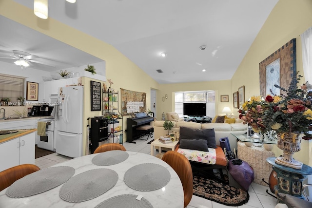 tiled dining space featuring ceiling fan, sink, and vaulted ceiling