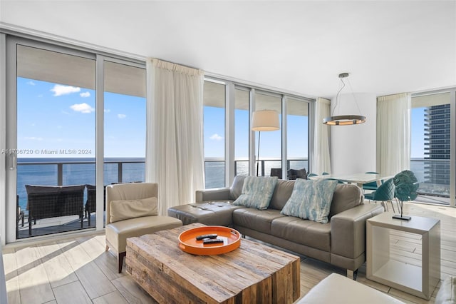 living room featuring a wall of windows, a water view, and light wood-type flooring