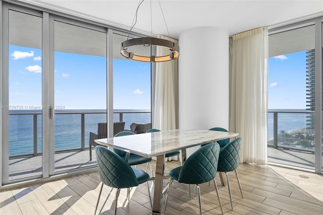 dining area featuring a water view, light hardwood / wood-style flooring, and expansive windows