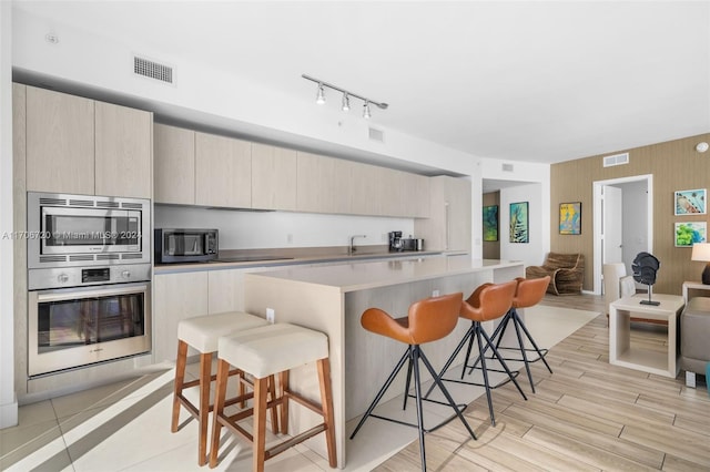 kitchen featuring a breakfast bar, appliances with stainless steel finishes, and light hardwood / wood-style flooring