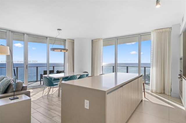 kitchen featuring a wall of windows, a water view, a kitchen island, and hanging light fixtures