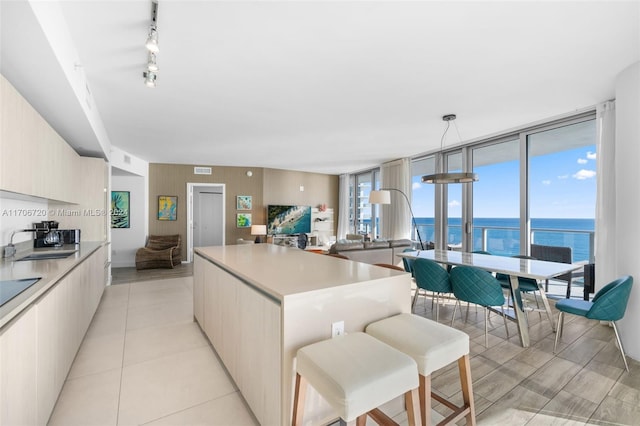 kitchen with pendant lighting, sink, light tile patterned floors, a kitchen island, and a wall of windows