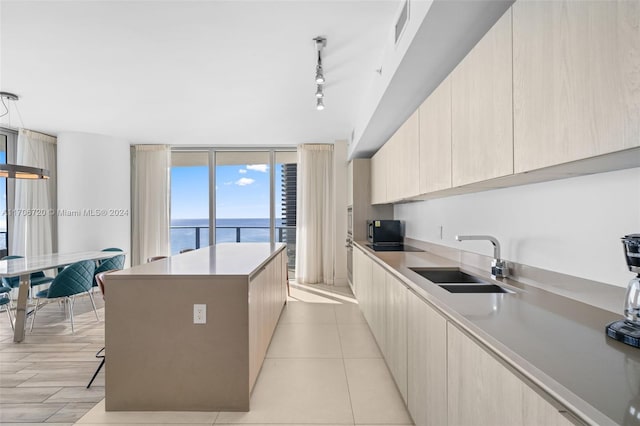 kitchen with a breakfast bar, a center island, a water view, sink, and decorative light fixtures