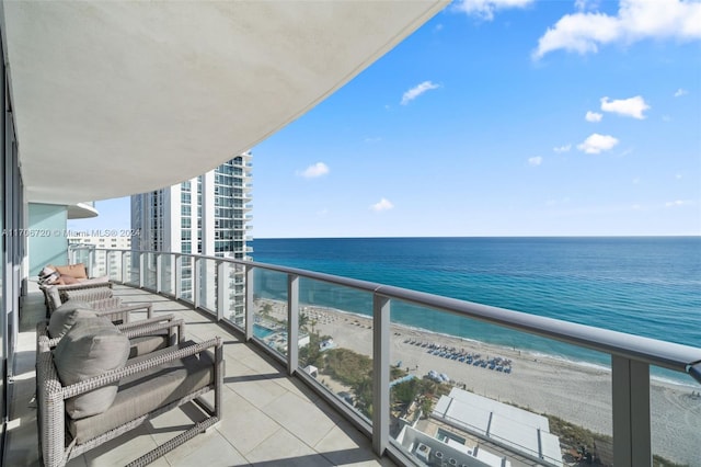 balcony with a water view and a view of the beach