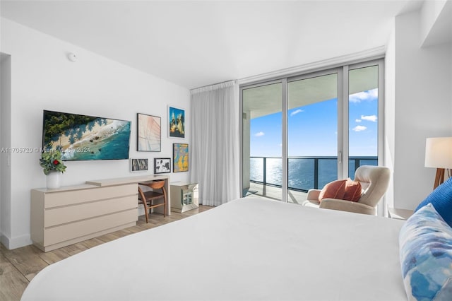 bedroom with access to exterior, light hardwood / wood-style flooring, and a water view