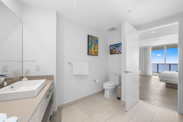 bathroom with toilet, a water view, wood-type flooring, and vanity