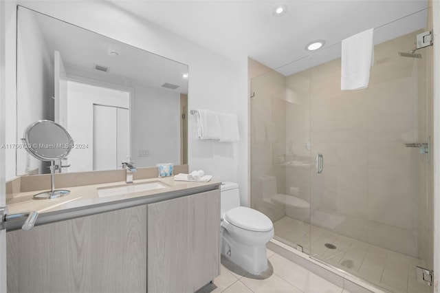 bathroom featuring tile patterned flooring, vanity, an enclosed shower, and toilet