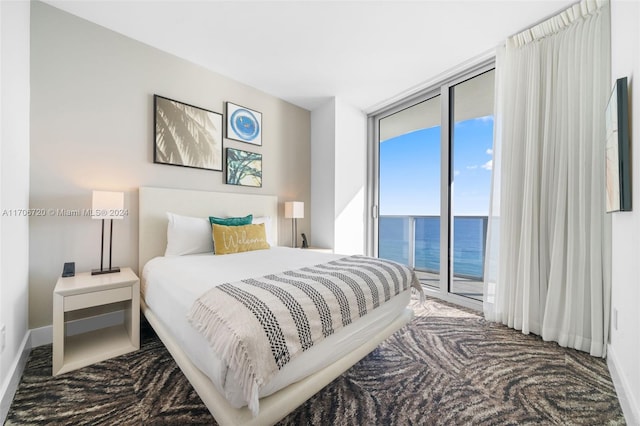 bedroom featuring access to exterior, a water view, and a wall of windows