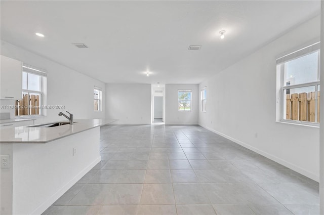 unfurnished living room featuring light tile patterned floors and sink