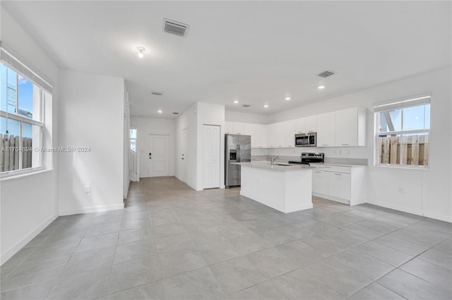 kitchen featuring a center island with sink, a healthy amount of sunlight, white cabinetry, and appliances with stainless steel finishes