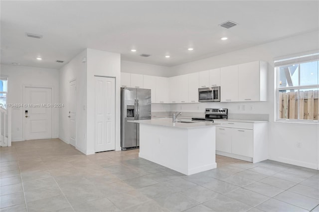 kitchen featuring white cabinets, light tile patterned flooring, a kitchen island with sink, and appliances with stainless steel finishes