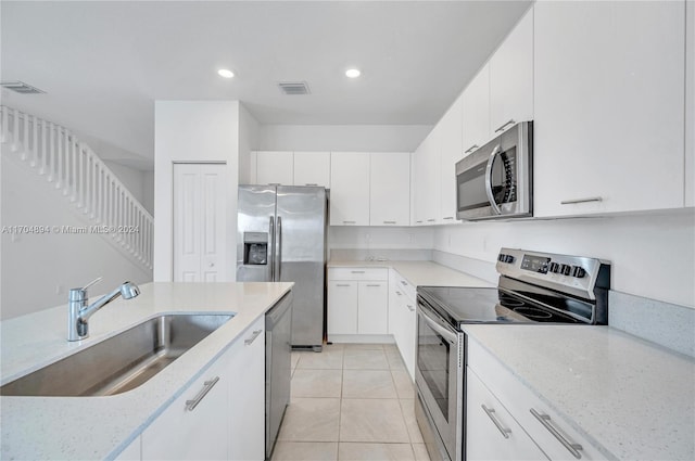 kitchen with light stone counters, sink, white cabinets, and stainless steel appliances