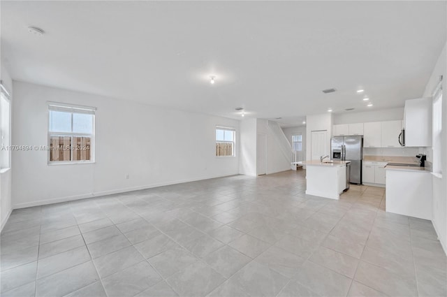 unfurnished living room with sink and light tile patterned floors