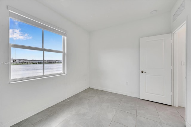 tiled spare room featuring a water view