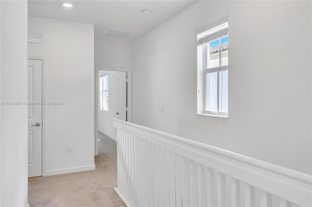 hall with light colored carpet and a healthy amount of sunlight