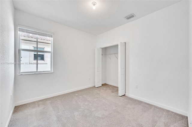 unfurnished bedroom featuring light carpet and a closet