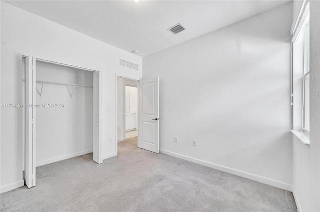 unfurnished bedroom featuring light carpet and a closet