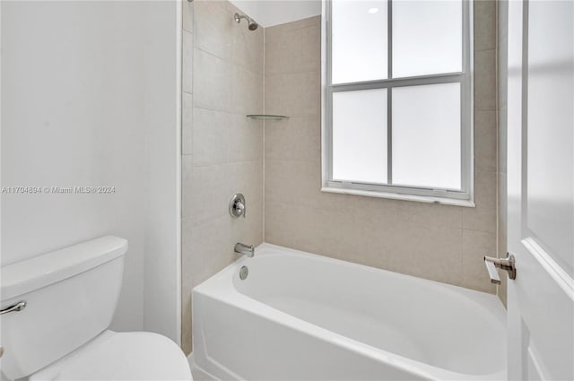 bathroom with toilet and tiled shower / bath