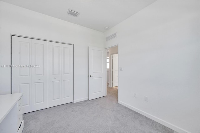 unfurnished bedroom featuring light colored carpet and a closet