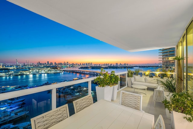 balcony at dusk featuring a water view