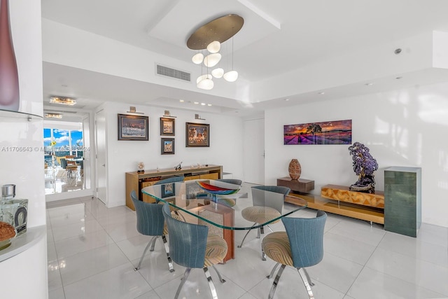 tiled dining room featuring a raised ceiling