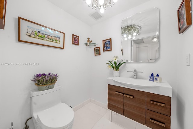 bathroom with tile patterned floors, vanity, toilet, and an inviting chandelier