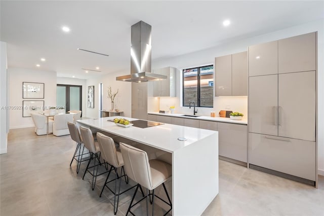 kitchen with island exhaust hood, black electric cooktop, sink, a center island, and a breakfast bar area